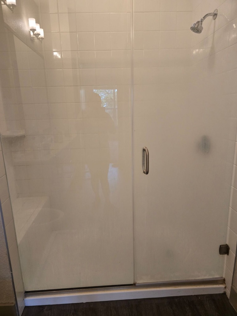 Dirty shower glass door before cleaning with soap scum