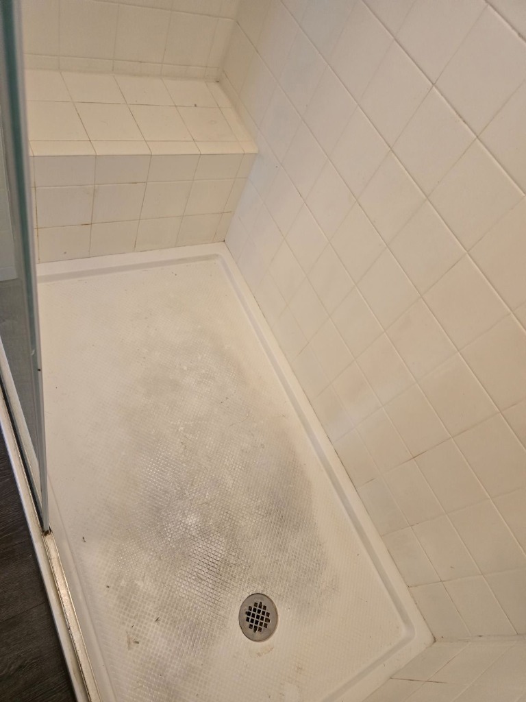 Stained shower floor tiles before deep cleaning
